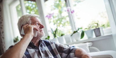 Older man talking on phone looking out window